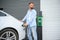 Stylish man inserts plug into the electric car charging socket