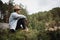 Stylish man sitting on edge of rocky slope among woods