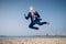 Stylish manager in funny mask and elegant suit jumps on beach