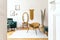 Stylish and minimalist interior of living room with design gold armchair, lamp, poster frames. dressing table with mirror, plants