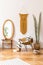Stylish and minimalist interior of living room with design gold armchair, lamp, poster frames. dressing table with mirror, plants.
