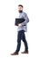 Stylish modern bearded business man holding laptop under arm walking. Side view