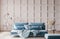 Stylish modern interior of living room with trending home accessories, marble coffee table, dried flowers, and blue sofa.