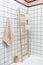 Stylish modern Scandinavian loft bathroom interior: white square tiles, towel rack, storage containers and cotton towel