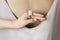 Stylish modern square pink ring on hand with white manicure, closeup. Woman in dress. Beauty care