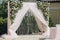 Stylish modern wedding arch with roses,tulle,stones, floral decorations at wedding reception outdoors. Luxury adorning