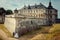 Stylish newlywed couple is holding hands near the wall of the huge old baroque castle.