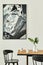 Stylish open space interior with wooden family table, black chairs, cups of coffee, tropical leaf in vase, abstract painting.