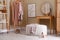 Stylish ottoman, console table and clothing rack in dressing room. Interior design