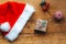 Stylish packaged Christmas gift box, Santa Claus hat and a sprig of spruce on a rustic wooden table. Atmospheric image. Merry