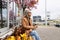 a stylish pensioner sits on a bench next to a store with a mobile phone in her hands and looks into the distance