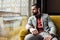 stylish pensive man sitting on yellow sofa