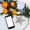 Stylish phone with empty screen and christmas oranges and golden