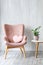 Stylish pink armchair with heart shaped pillow in a bright minimalist interior.