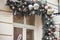 Stylish pink baubles on christmas fir branches arrangement on window on building exterior. Modern christmas decor in city street.