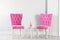 Stylish pink chairs and table near white wall