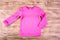 Stylish pink child sweater on wooden background