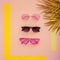Stylish pink sunglasses collection. Summer funky glasses on pink background with gold palm leaves. Top View. Flat lay