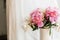 Stylish pink and white peonies in vase. Hello spring. Lovely peony bouquet in sunny light on rustic wooden window sill. Happy