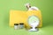 Stylish pocket mirror and cosmetic bag with makeup products on light green background