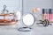 Stylish pocket mirror and cosmetic products on grey table