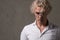 Stylish portrait of a young young man in glasses with white curly hair on a gray background.