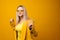 Stylish positive young woman on yellow background, copy space.