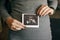 Stylish pregnant woman holding ultrasound scan of her baby on her baby bump. Healthy young woman holding in hands on belly photo