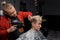Stylish professional European man barber blow-drying hair for a client guy in a haircut in a barbershop