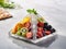 Stylish pyramid-shaped plate with frozen fruits on light marble table