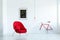 Stylish red armchair in an empty living room interior with a black painting, lamp and bike. Place your product