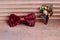 Stylish red bow and boutonniere on wooden background, groom getting ready in morning before the wedding.