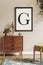 Stylish retro composition of living room with black mock up poster frame, vintage commode and pouf, plants and elegant personal.