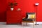 Stylish room interior with  furniture and houseplant near red wall