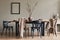 Stylish rustic interior of dining room with walnut wooden table, retro chairs, decoration, fireplace, dried flower, candlestick.