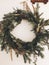 Stylish rustic wreath on white wall. Rural modern wreath hanging white wall background in room. Happy Holidays. Festive decoration