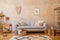 Stylish scandi compostion at living room interior with design gray sofa, wooden coffee table, shelf, cube, carpet, rattan decor.