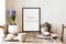 Stylish scandi interior design of kitchen space with small table with mock up frame, plant, cups of tea and tasty dessert.