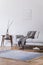 Stylish scandi interior of home space with design grey sofa, retro wooden table, mock up poster frame, decoration , carpet.