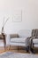 Stylish scandi interior of home space with design grey sofa, retro wooden table, mock up poster frame, decoration , carpet.