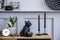 Stylish scandinavian composition with wooden commode, design plant pot, retro photo camera, books, cacti, decoration.