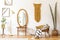 Stylish and scanidnavian interior of apartment with big mirror, dressing table, gold armchair, design accessories, furniture,