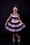 Stylish schoolgirl in a lush dress posing on a black background