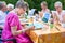 Stylish senior lady painting in art class with friends from her care home for the aged copying a painting with water colors.