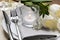 Stylish setting with cutlery, burning candle and tulips on table, closeup