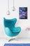 Stylish silver lamps above blue egg chair in modern living room interior with cosmos graphic on the wall, real photo
