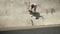 Stylish skateboarder doing skateboard trick on old wall