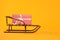 Stylish sleigh with Christmas gift on yellow background, space for text
