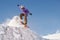 Stylish snowboarder with helmet and mask jumps from high snow slope