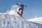 Stylish snowboarder with helmet and mask jumps from high snow slope